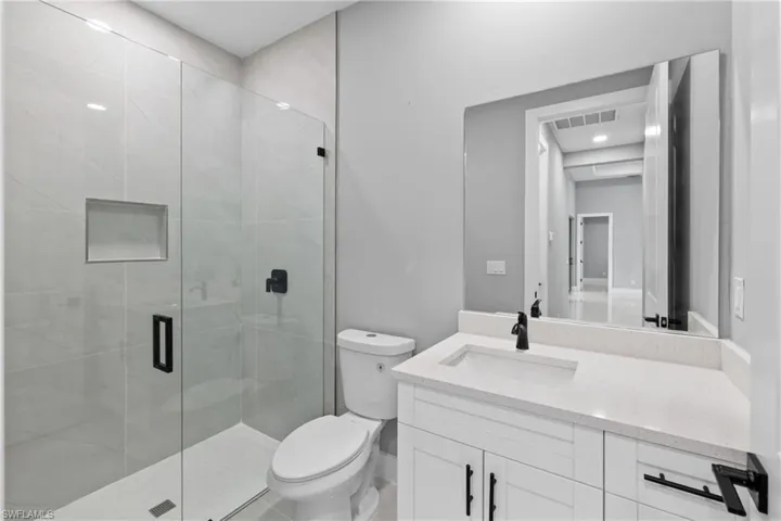 Bathroom with vanity, toilet, and a shower with door
