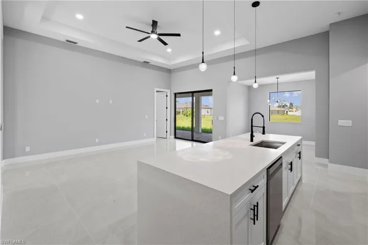 Kitchen featuring a raised ceiling, hanging light fixtures, a wealth of natural light, and sink