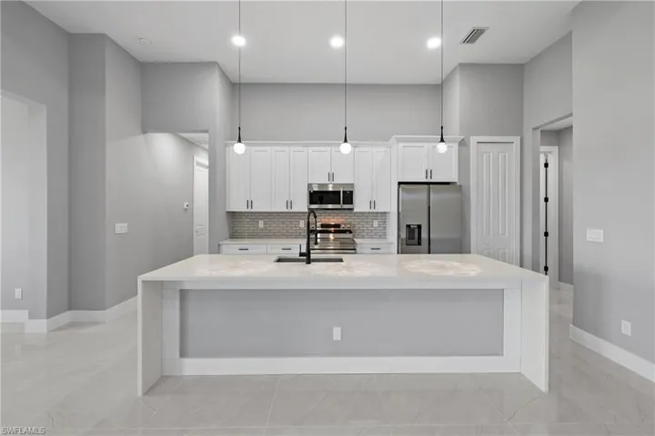 Kitchen featuring appliances with stainless steel finishes, decorative backsplash, light tile patterned floors, and a large island