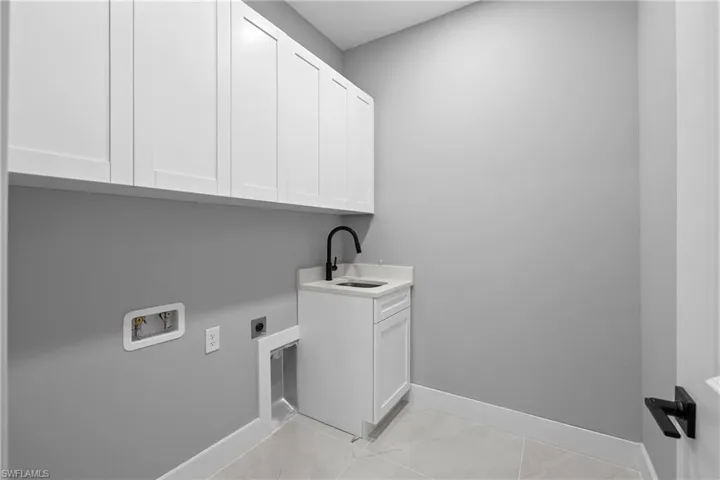 Laundry room featuring sink, cabinets, light tile patterned floors, hookup for an electric dryer, and washer hookup