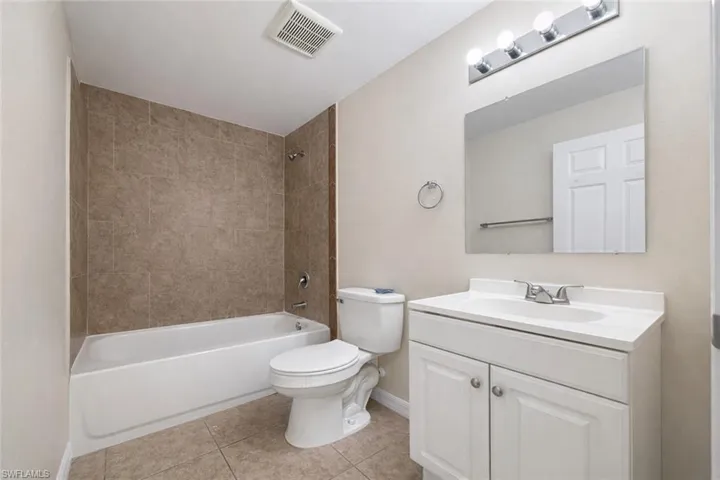 Bathroom with bathtub / shower combination, vanity, and light tile patterned floors