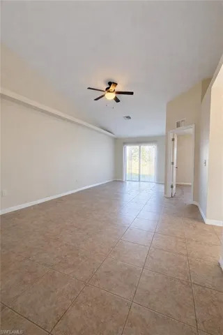 Empty room with a ceiling fan and light tile patterned flooring