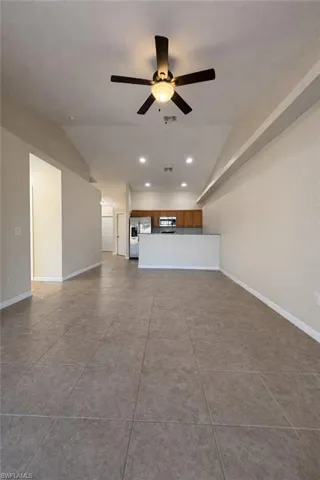 Unfurnished living room with vaulted ceiling, recessed lighting, ceiling fan, and light tile patterned flooring