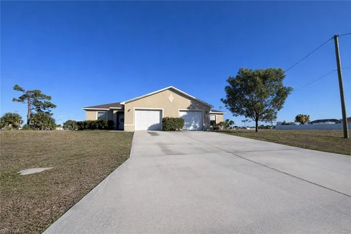 Ranch-style house featuring stucco siding, a front yard, driveway, and a garage