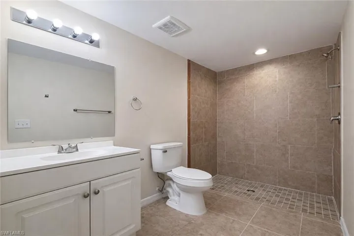 Full bathroom featuring vanity, a tile shower, light tile patterned floors, and recessed lighting