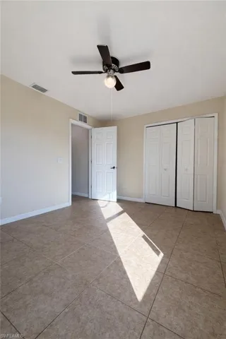 Unfurnished bedroom with light tile patterned floors, a closet, and ceiling fan