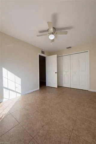 Unfurnished bedroom featuring a ceiling fan, a closet, and light tile patterned flooring