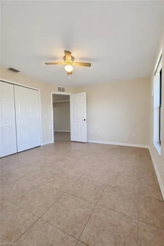 Unfurnished bedroom featuring a closet, a ceiling fan, and light tile patterned floors