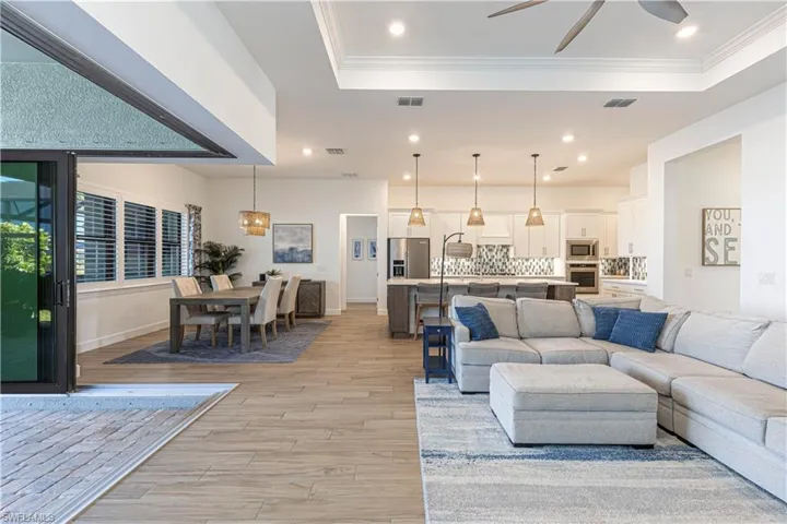 Living room featuring ornamental molding, visible vents, a raised ceiling, and light wood finished floors
