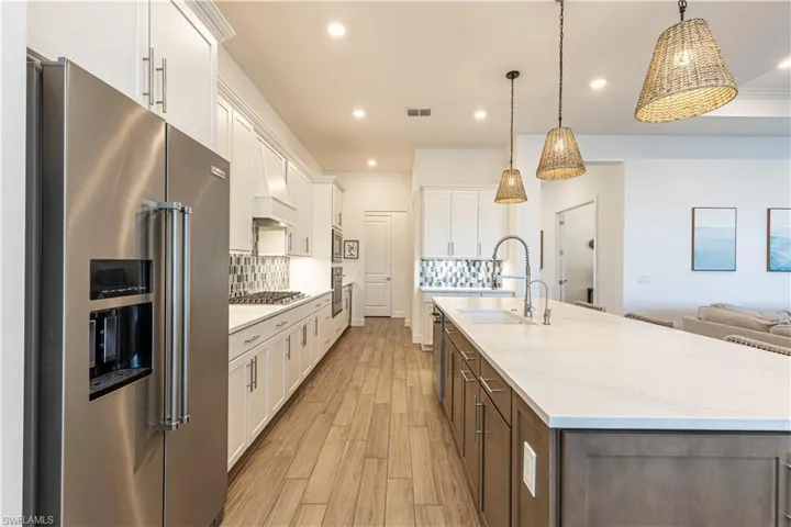 Kitchen featuring light wood-style flooring, tasteful backsplash, white cabinetry, appliances with stainless steel finishes, and a sink