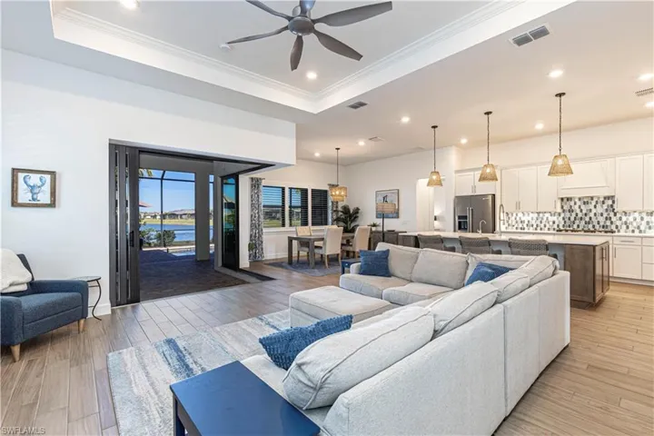 Living area featuring a tray ceiling, ceiling fan, visible vents, and recessed lighting