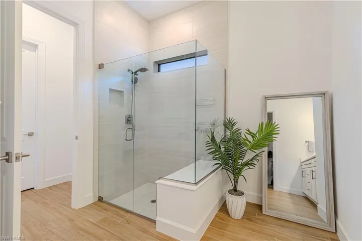 Full bath with baseboards, a stall shower, and wood finished floors