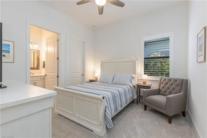 Bedroom with ensuite bath, ceiling fan, light colored carpet, and baseboards