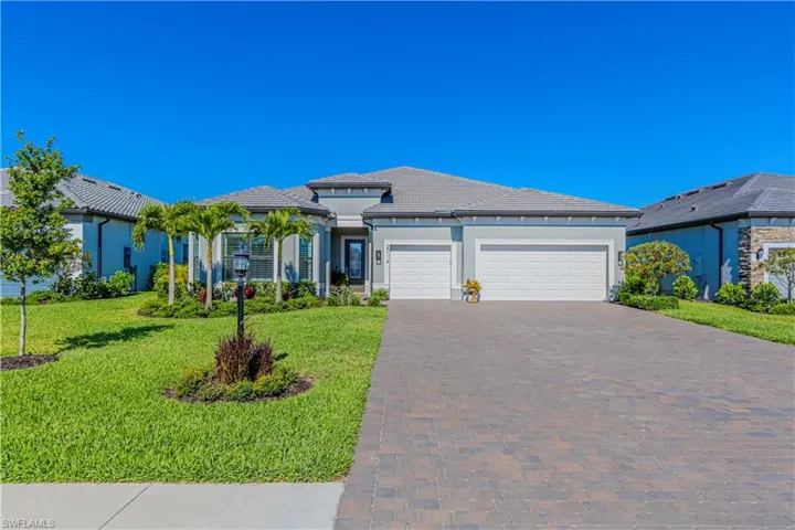Prairie-style house with stucco siding, driveway, a front yard, a tile roof, and a garage