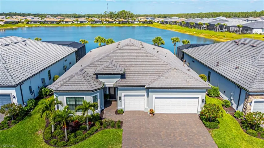 View of front of house featuring a water view, a tiled roof, an attached garage, stucco siding, and a residential view