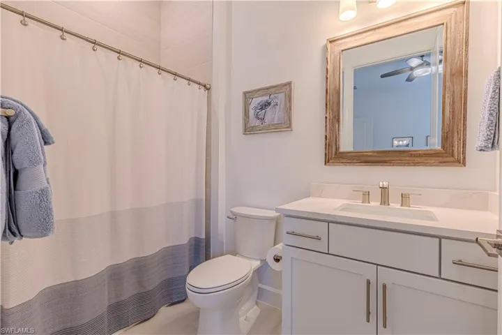 Full bath featuring curtained shower, vanity, baseboards, and toilet