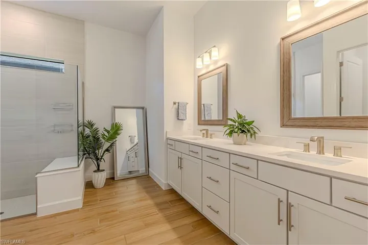 Full bathroom with a sink, a walk in shower, double vanity, and wood finished floors