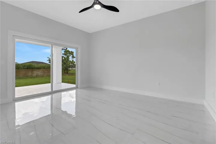 Tiled empty room with ceiling fan and plenty of natural light