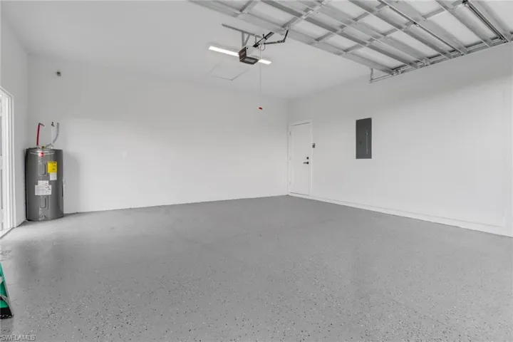 Garage with a garage door opener, water heater, and electric panel
