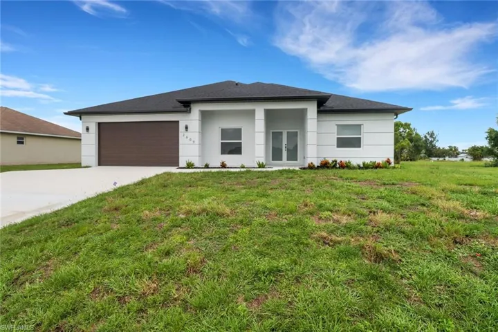 View of front of house featuring a front lawn and a garage