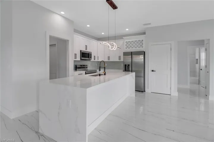 Kitchen with light tile patterned flooring, stainless steel appliances, pendant lighting, and white cabinets