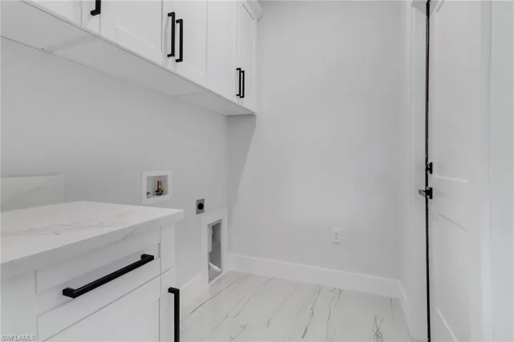 Washroom with electric dryer hookup, washer hookup, and cabinets