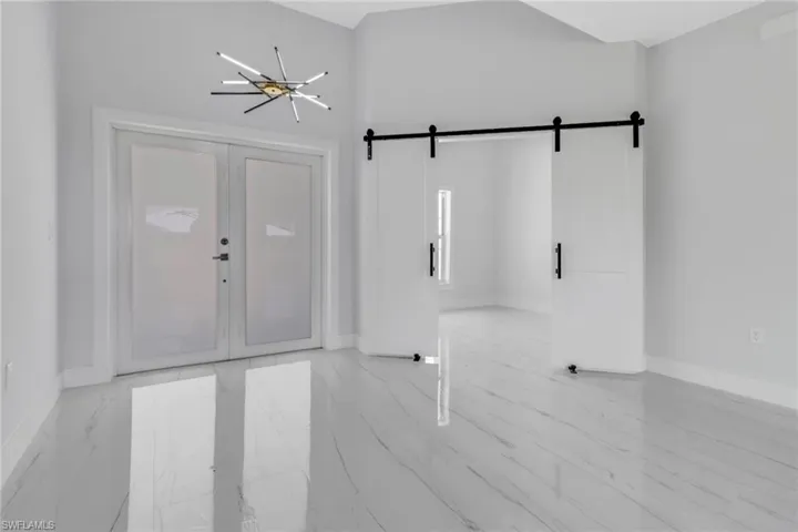 Spare room featuring light tile patterned flooring, an inviting chandelier, and a barn door
