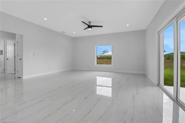 Empty room featuring a wealth of natural light, ceiling fan, and light tile patterned flooring