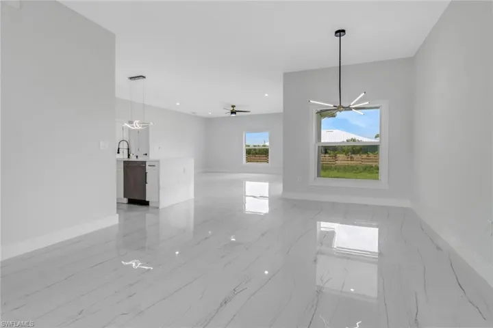 Unfurnished living room with sink, ceiling fan with notable chandelier, and light tile patterned flooring