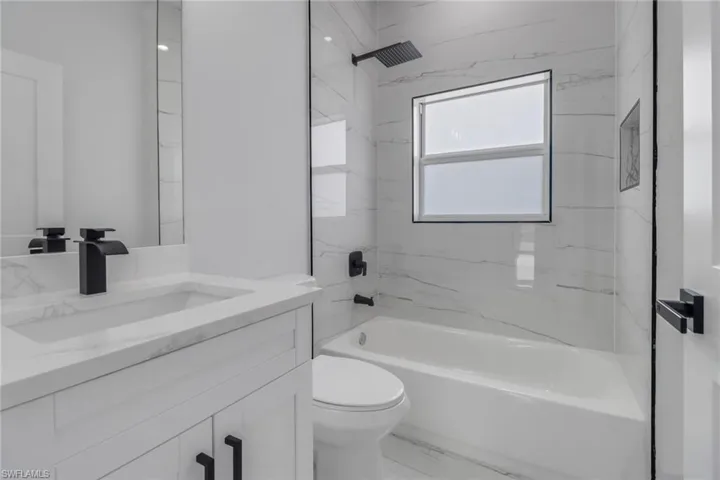 Full bathroom with tiled shower / bath, vanity, and toilet