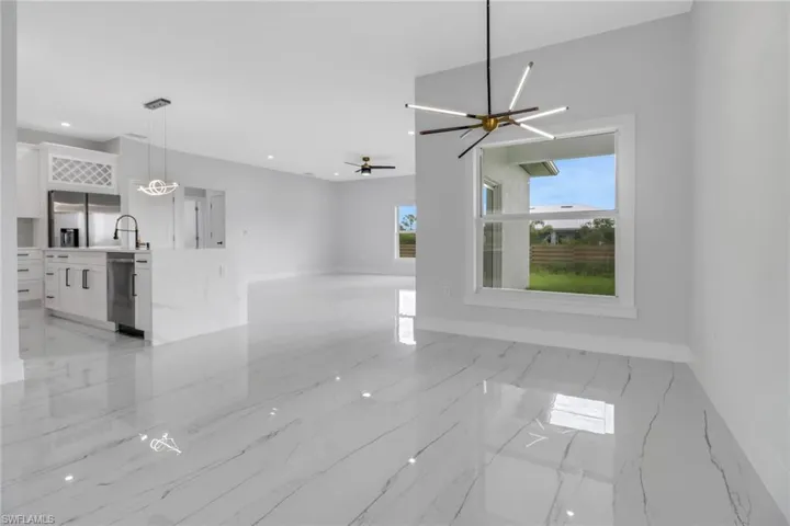 Unfurnished living room featuring light tile patterned floors and ceiling fan with notable chandelier