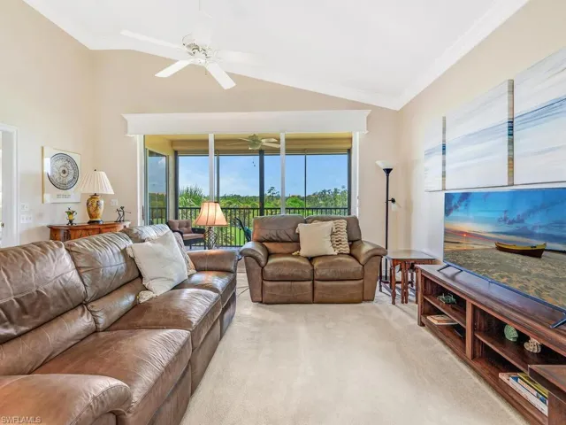 Living room featuring crown molding, carpet, ceiling fan, and vaulted ceiling