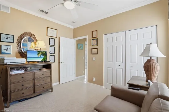 Living area featuring ornamental molding, light colored carpet, and ceiling fan