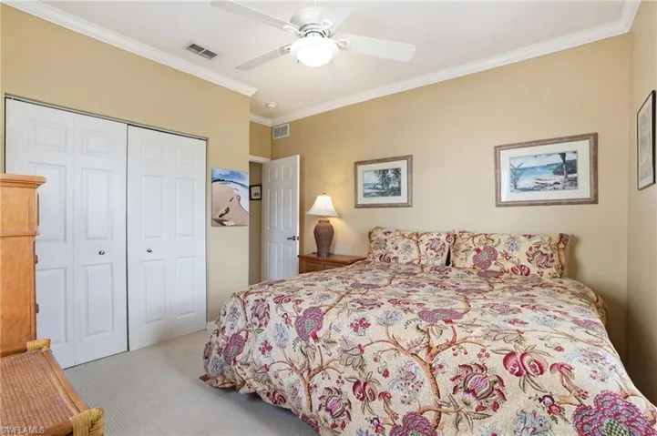 Bedroom with crown molding, a ceiling fan, light colored carpet, and a closet