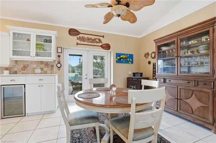Dining area with beverage cooler, french doors, crown molding, light tile patterned floors, and ceiling fan