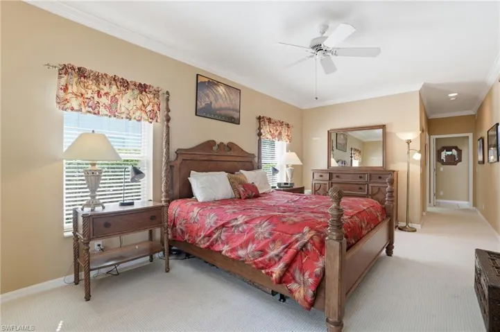 Bedroom with light carpet, ornamental molding, multiple windows, and ceiling fan