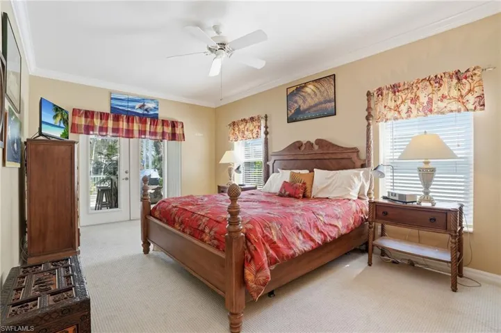 Bedroom featuring access to outside, light colored carpet, multiple windows, ceiling fan, and ornamental molding