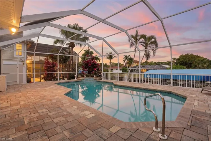 Outdoor pool featuring a sunroom, glass enclosure, and a patio