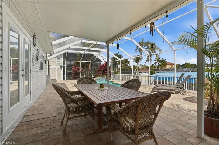 View of patio / terrace featuring glass enclosure, a sunroom, outdoor dining area, an outdoor pool, and a water view