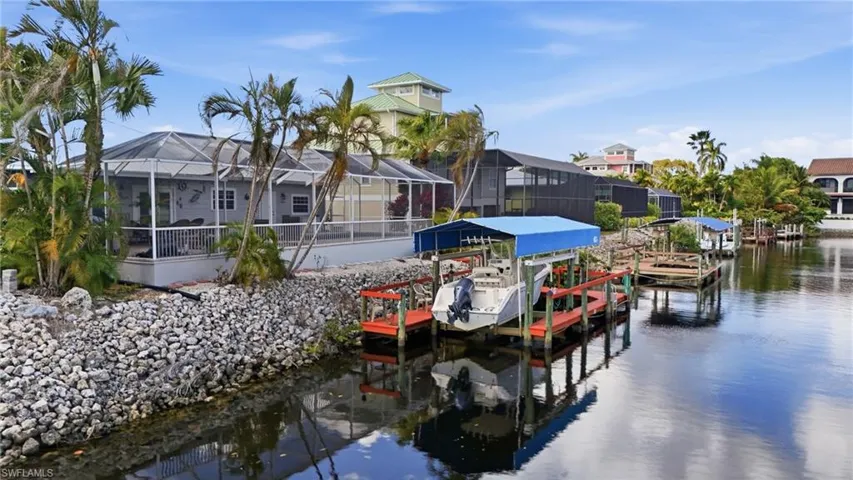 Dock area with boat lift, a water view, a lanai, and a sunroom