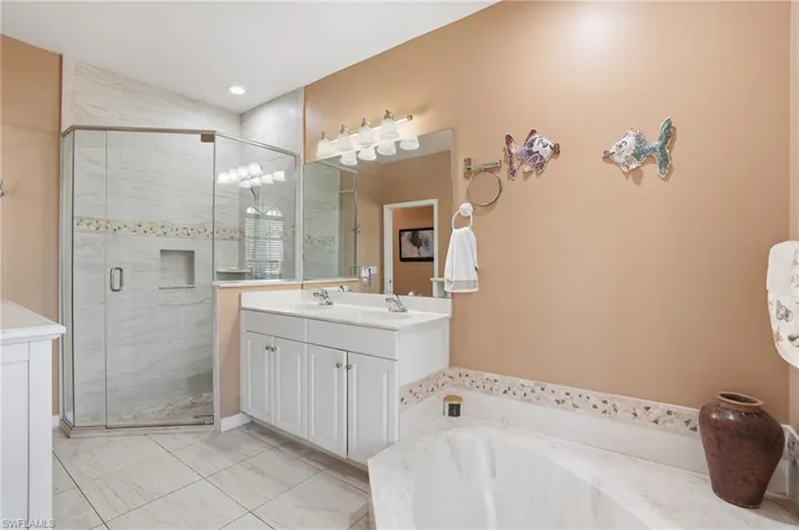 Full bath featuring double vanity, a shower stall, and a garden tub