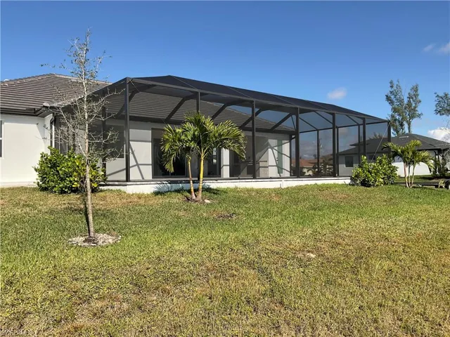 Back of property with a lanai and a lawn