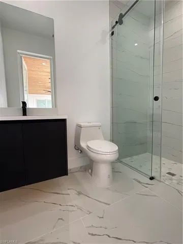 Bathroom with vanity, an enclosed shower, and toilet