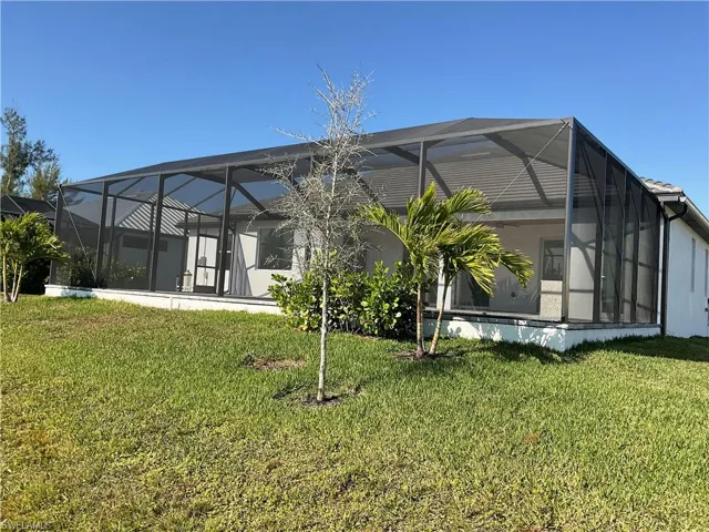 Rear view of property featuring a lanai and a yard