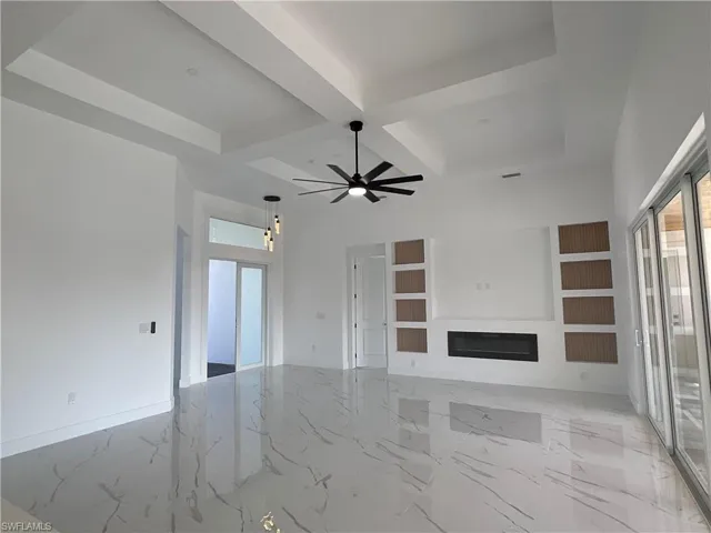 Unfurnished living room featuring ceiling fan, beam ceiling, and coffered ceiling