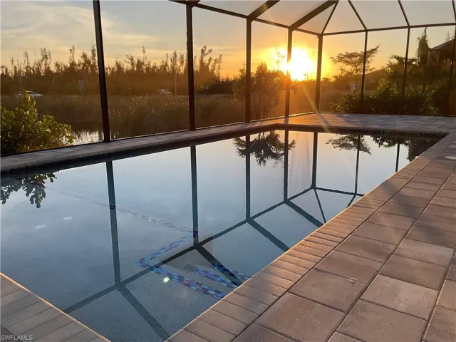 Pool at dusk with a patio area and a lanai