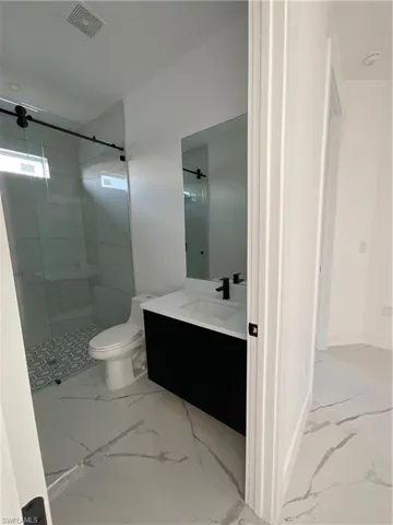Bathroom with vanity, toilet, and tiled shower