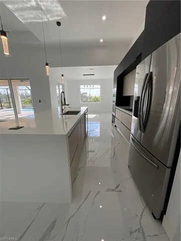 Kitchen with a large island, sink, pendant lighting, and fridge