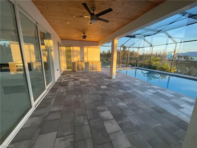 View of patio with an outdoor kitchen, ceiling fan, and a lanai
