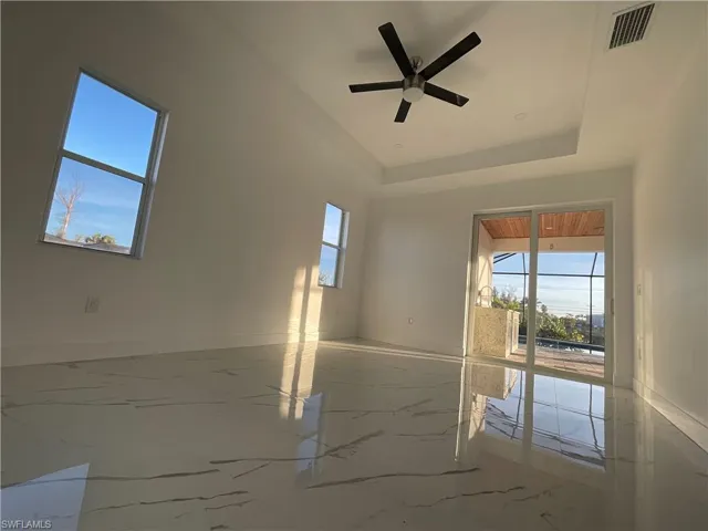 Unfurnished room featuring a raised ceiling and ceiling fan
